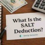 A financial workspace with a notepad, pen, calculator, cash, and coins on a wooden desk. A paper reads “What Is the SALT Deduction?” with a oneupnetworks logo visible in the bottom right corner.