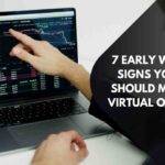 A person points at financial charts on a laptop screen displaying market data and graphs. Text on the image reads “7 Early Warning Signs Your Firm Should Move Off Virtual Office CS.”