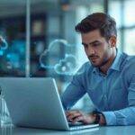 A focused man working on a laptop in a bright, modern office with sunlight streaming through large windows, representing productivity and secure cloud data management.